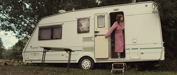 Movie still from “Sightseers” (2012), directed by Ben Wheatley – A woman standing in the doorway of a camper; Wide shot, Low angle