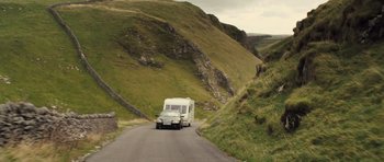 Movie still from “Sightseers” (2012), directed by Ben Wheatley – An rv traveling down a road in the mountains; Extreme Wide shot, High angle