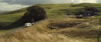 Movie still from “Sightseers” (2012), directed by Ben Wheatley – A truck driving down a road on a grassy hill; Extreme Wide shot, High angle
