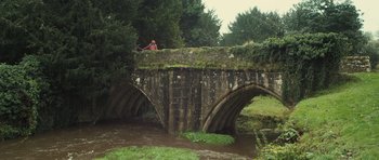 Movie still from “Sightseers” (2012), directed by Ben Wheatley – A person standing on a bridge over a river; Extreme Wide shot, Low angle