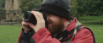 Movie still from “Sightseers” (2012), directed by Ben Wheatley – A man taking a picture with a camera; Extreme Close Up shot, Low angle
