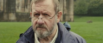 Movie still from “Sightseers” (2012), directed by Ben Wheatley – An older man with a beard and glasses; Close Up shot, Over the shoulder angle