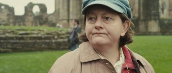Movie still from “Sightseers” (2012), directed by Ben Wheatley – An older woman wearing a hat and a jacket; Close Up shot, Over the shoulder angle