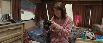 Movie still from “Sightseers” (2012), directed by Ben Wheatley – A woman holding a camera in a room; Medium shot, High angle