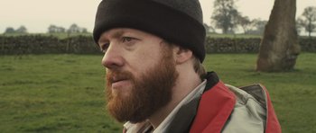 Movie still from “Sightseers” (2012), directed by Ben Wheatley – A person with a beard wearing a hat; Close Up shot, Over the shoulder angle