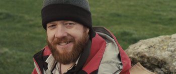Movie still from “Sightseers” (2012), directed by Ben Wheatley – A person with a beard wearing a hat; Close Up shot, Over the shoulder angle