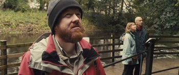 Movie still from “Sightseers” (2012), directed by Ben Wheatley – A man with a red beard and a red jacket; Medium shot, Over the shoulder angle
