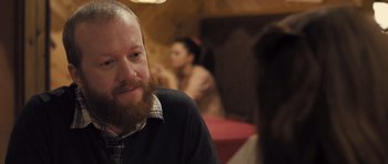 Movie still from “Sightseers” (2012), directed by Ben Wheatley – A man with a beard sitting in front of a woman; Close Up shot, Over the shoulder angle
