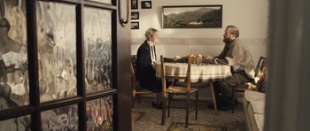 Movie still from “Sightseers” (2012), directed by Ben Wheatley – Two people sitting at a dining room table; Wide shot, High angle