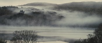 Movie still from “Sightseers” (2012), directed by Ben Wheatley – A body of water surrounded by trees and fog; Extreme Wide shot, High angle