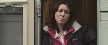 Movie still from “Sightseers” (2012), directed by Ben Wheatley – A woman standing in front of an open door; Close Up shot, Over the shoulder angle
