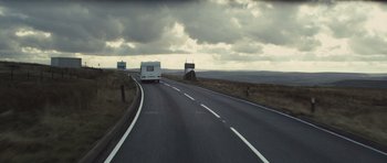 Movie still from “Sightseers” (2012), directed by Ben Wheatley – A white van driving down a road near a grassy hill; Extreme Wide shot, Low angle