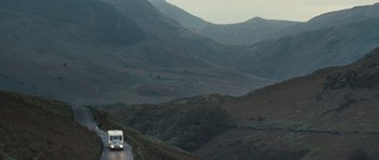 Movie still from “Sightseers” (2012), directed by Ben Wheatley – A bus driving down a road in the middle of a valley; Extreme Wide shot, High angle