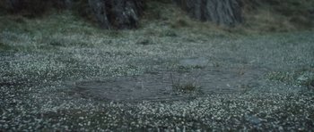 Movie still from “Sightseers” (2012), directed by Ben Wheatley – A puddle of water on the side of a road; Extreme Wide shot, High angle