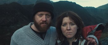 Movie still from “Sightseers” (2012), directed by Ben Wheatley – A man and a woman standing next to each other in front of mountains; Close Up shot, Low angle