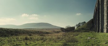 Movie still from “Sightseers” (2012), directed by Ben Wheatley – A grassy field with a mountain in the background; Extreme Wide shot, Low angle