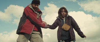 Movie still from “Sightseers” (2012), directed by Ben Wheatley – A man and a woman holding hands while standing on a hill; Medium shot, Low angle