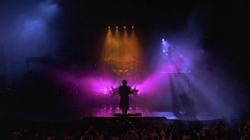 Movie still from “Sign 'o' the Times” (1987), directed by Albert Magnoli – A man standing on a stage in front of a crowd; Extreme Wide shot, Low angle