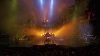 Movie still from “Sign 'o' the Times” (1987), directed by Albert Magnoli – A man playing a guitar on a stage with lights; Extreme Wide shot, High angle