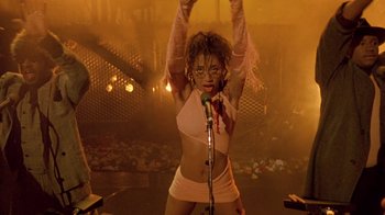 Movie still from “Sign 'o' the Times” (1987), directed by Albert Magnoli – A woman is holding a microphone in her hand; Medium shot, High angle