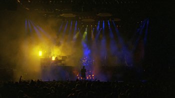 Movie still from “Sign 'o' the Times” (1987), directed by Albert Magnoli – A person standing in front of a stage with lights; Extreme Wide shot, High angle