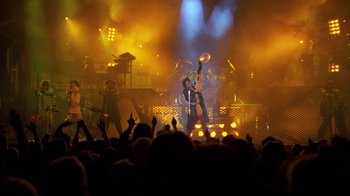 Movie still from “Sign 'o' the Times” (1987), directed by Albert Magnoli – A crowd of people watching a band perform on a stage; Extreme Wide shot, High angle