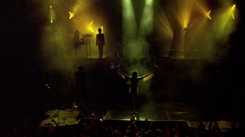 Movie still from “Sign 'o' the Times” (1987), directed by Albert Magnoli – A crowd of people are watching a person on a stage; Wide shot, Overhead angle