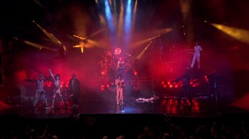 Movie still from “Sign 'o' the Times” (1987), directed by Albert Magnoli – A group of people on a stage with lights in the background; Extreme Wide shot, High angle