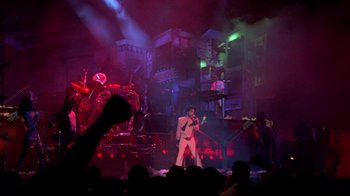 Movie still from “Sign 'o' the Times” (1987), directed by Albert Magnoli – A man in a white suit is on a stage; Extreme Wide shot, Low angle
