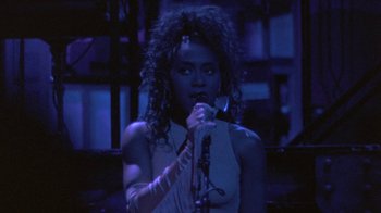 Movie still from “Sign 'o' the Times” (1987), directed by Albert Magnoli – A woman holding a microphone in her hand; Close Up shot, Low angle