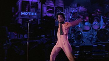 Movie still from “Sign 'o' the Times” (1987), directed by Albert Magnoli – A man in a pink suit and a microphone; Wide shot, Low angle