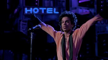 Movie still from “Sign 'o' the Times” (1987), directed by Albert Magnoli – A man standing in front of a microphone on a stage; Medium shot, Low angle