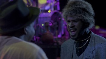 Movie still from “Sign 'o' the Times” (1987), directed by Albert Magnoli – A man in a fur hat talking to another man in a suit; Close Up shot, Low angle