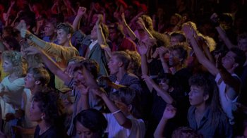Movie still from “Sign 'o' the Times” (1987), directed by Albert Magnoli – A group of people standing in front of an audience; Wide shot, High angle