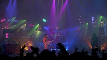 Movie still from “Sign 'o' the Times” (1987), directed by Albert Magnoli – A crowd of people watching a band perform on a stage; Wide shot, High angle