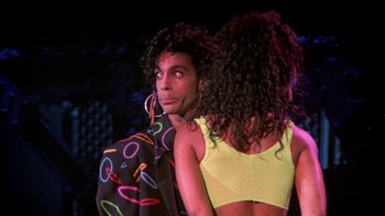 Movie still from “Sign 'o' the Times” (1987), directed by Albert Magnoli – A person wearing a yellow top; Medium shot, Over the shoulder angle