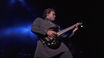Movie still from “Sign 'o' the Times” (1987), directed by Albert Magnoli – A man playing a guitar on a stage; Medium shot, Low angle