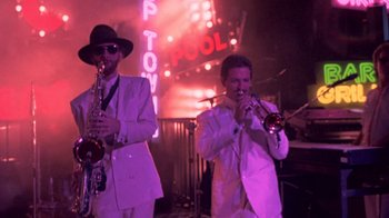 Movie still from “Sign 'o' the Times” (1987), directed by Albert Magnoli – A couple of men in white suits playing musical instruments; Wide shot, Low angle