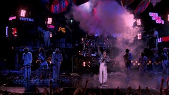 Movie still from “Sign 'o' the Times” (1987), directed by Albert Magnoli – A group of people on a stage performing; Extreme Wide shot, High angle