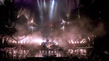 Movie still from “Sign 'o' the Times” (1987), directed by Albert Magnoli – A man playing a guitar in front of an audience; Extreme Wide shot, High angle