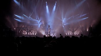 Movie still from “Sign 'o' the Times” (1987), directed by Albert Magnoli – A man standing in front of a microphone on a stage; Extreme Wide shot, High angle