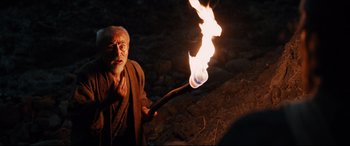 Movie still from “Silence” (2016), directed by Martin Scorsese – An old man holding a lit stick with fire; Medium shot, High angle