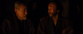 Movie still from “Silence” (2016), directed by Martin Scorsese – Two men are sitting next to each other in the dark; Close Up shot, Over the shoulder angle