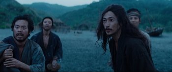Movie still from “Silence” (2016), directed by Martin Scorsese – Two people standing in a field with mountains in the background; Medium shot, Over the shoulder angle