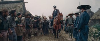 Movie still from “Silence” (2016), directed by Martin Scorsese – A man sitting on top of a horse next to a crowd of people; Wide shot, Low angle