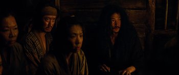 Movie still from “Silence” (2016), directed by Martin Scorsese – A group of people sitting next to each other in a dark room; Medium shot, High angle