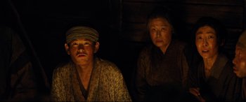 Movie still from “Silence” (2016), directed by Martin Scorsese – A man and a woman sitting next to each other; Medium shot, High angle