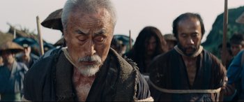 Movie still from “Silence” (2016), directed by Martin Scorsese – An old man with a beard is looking at the camera; Close Up shot, Over the shoulder angle