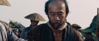 Movie still from “Silence” (2016), directed by Martin Scorsese – A man with a beard is wearing a hat; Close Up shot, Low angle