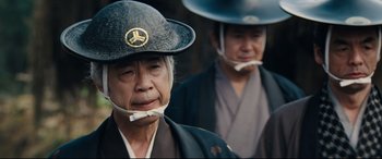 Movie still from “Silence” (2016), directed by Martin Scorsese – Two older men in traditional japanese garb and hats; Close Up shot, Low angle